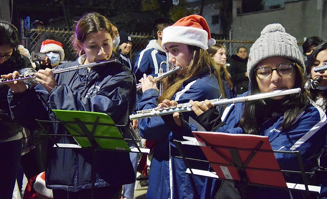 Port Chester High School Band flutists Rylie Heffernan, a senior, Gwen Dominguez, a junior, and Michelle Salazar, a senior, play a festive tune along with other band members gathered in the square to welcome the holiday season. 