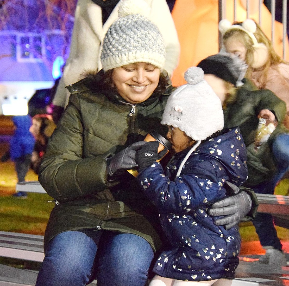 Carlton Lane resident Swati Kawli helps her 3-year-old daughter Moira warm up with some sips of hot chocolate.