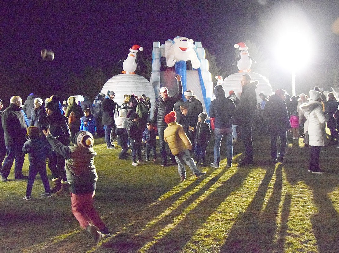 Children play while parents mingle in front of the giant inflatable winter obstacle course set up in Pine Ridge Park. 