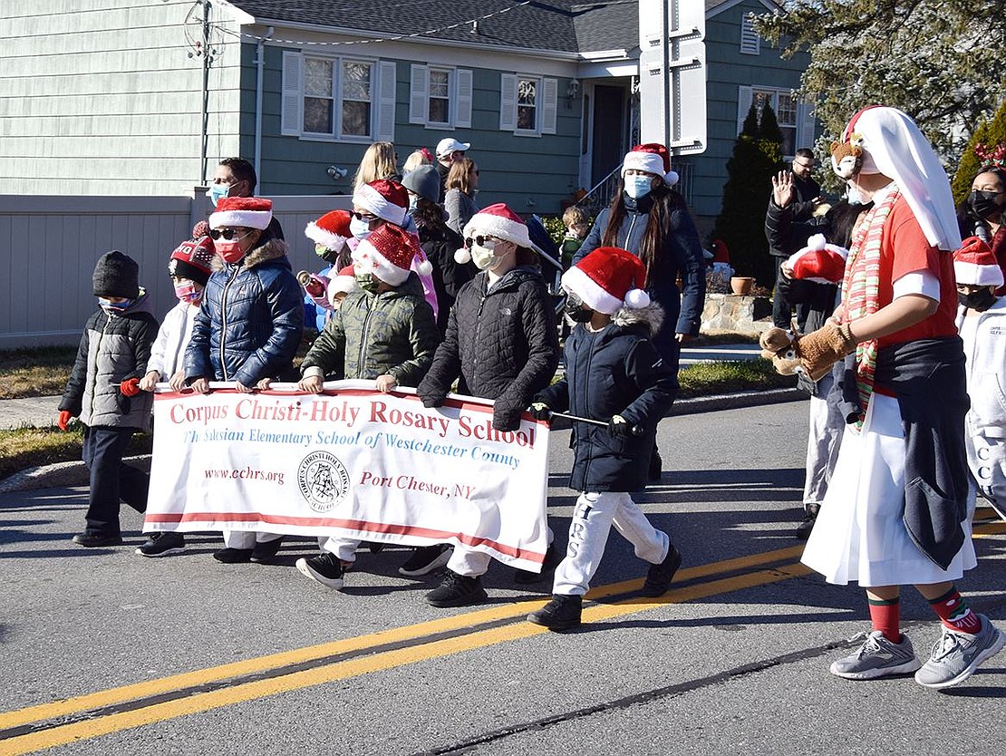 Corpus Christi-Holy Rosary School students cozy up with warm coats and Santa hats as they exhibit school pride in the holiday procession.