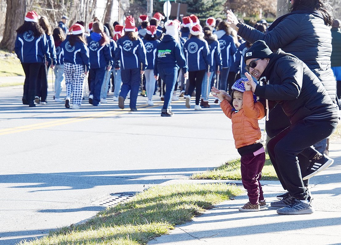 Victor Chavez and his 2-year-old daughter Lucy, New York City residents visiting family in Port Chester, dance to the music and wave as the parade passes them by.