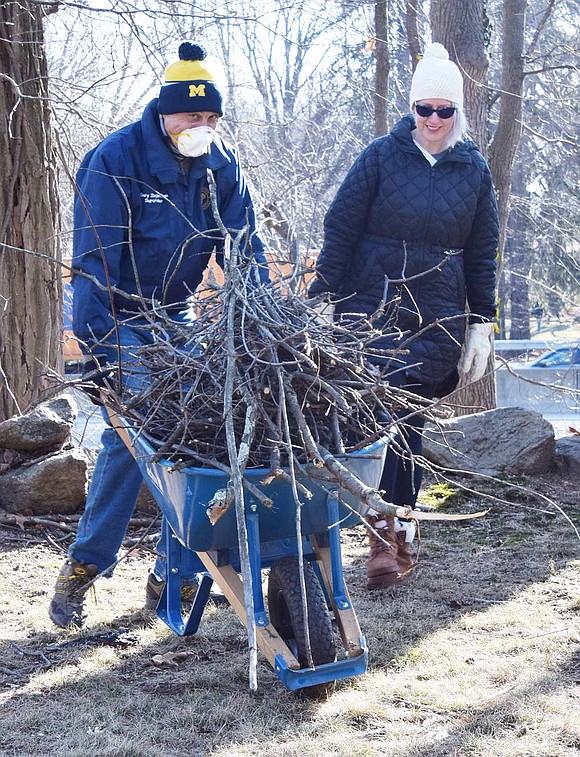 Rye Town Supervisor Gary Zuckerman, accompanied by Rye Town Councilwoman Pam Jaffee, pushes a wheelbarrow full of loose branches picked up around the cemetery to a Rye Town Parks Department truck onsite where staff members were loading up leaves, sticks and other debris cleaned up on Jan. 23 and carting it away.