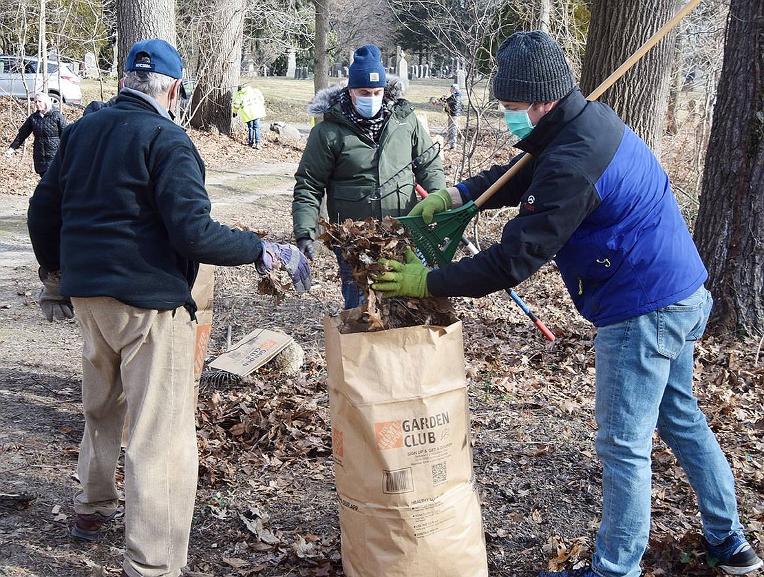 Matthew Anderson, president and CEO of The Osborn retirement community (right) in Rye, puts leaves he had raked up into a biodegradable bag. At left is Bill Dadlini, director of facilities at The Osborn, and behind them is Richard Scaglio, also from The Osborn. Rye Town Clerk Hope Vespia recently discovered from an old map that the path leading into the cemetery and the adjacent swamp are owned by The Osborn while the cemetery itself is owned by the Town of Rye. So maintenance of the African American Cemetery has become a partnership between the two.