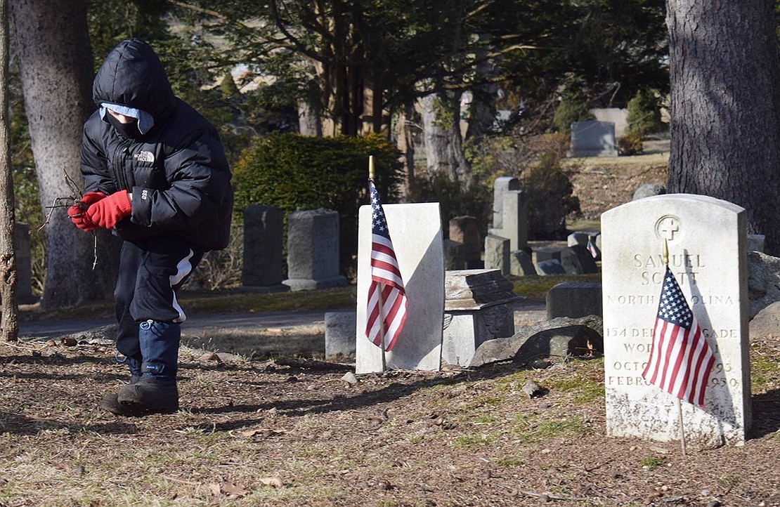 Eight-year-old Elliott Klein picks up sticks around gravestones at the cemetery. Rye Brook Trustee Jason Klein brought his whole family to the cleanup, including Elliott, son Alexander, 11, and wife Judy.