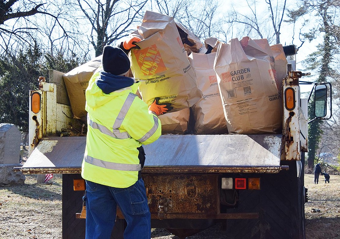 Vic Federico, head of the Town of Rye grounds and maintenance staff, loads a bag of debris cleaned up at the cemetery onto a track to be removed from the site.