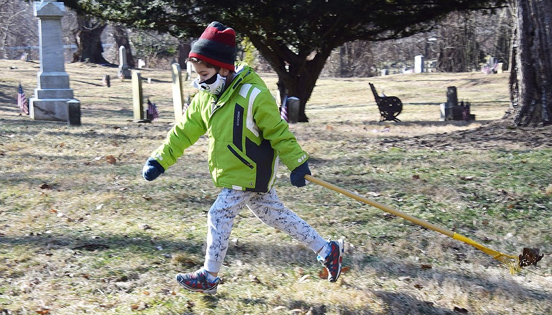 George Beltas, 6, of Rye Brook, runs through the cemetery with a rake, taking it to his father Periklis for instruction on how to help with the cemetery cleanup.