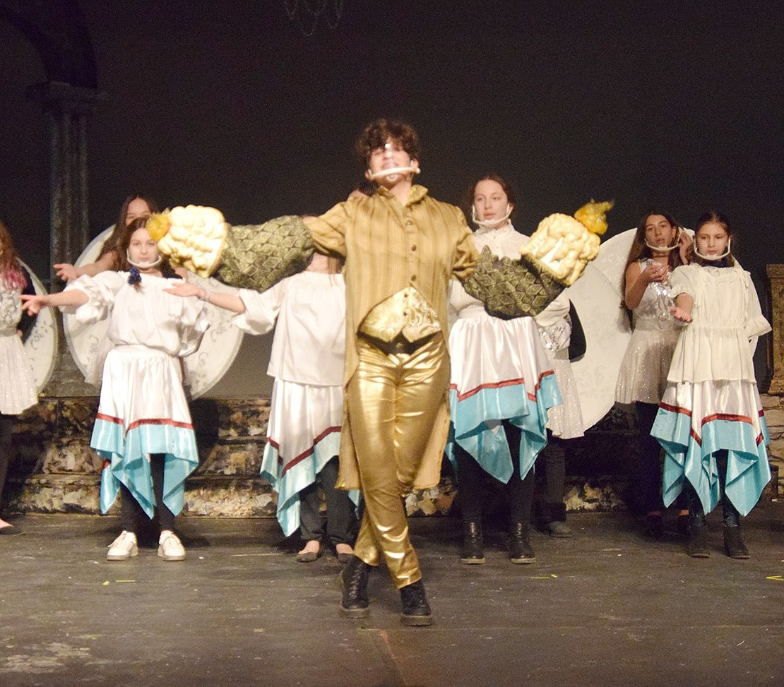 With an ensemble of plates and dining utensils behind him, Lumiere (played by Cassandra Brunetti) extravagantly welcomes Belle to the castle with the song “Be Our Guest.” 