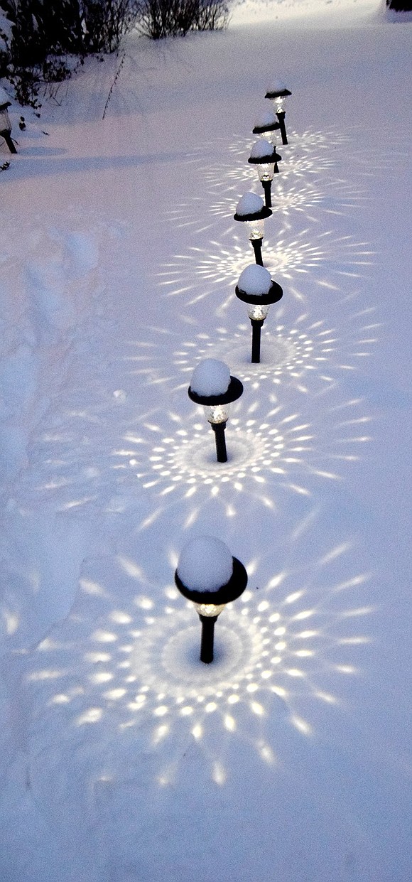 Reflections from lights in the front yard of a house on Quintard Drive dance on the new-fallen snow Saturday evening.