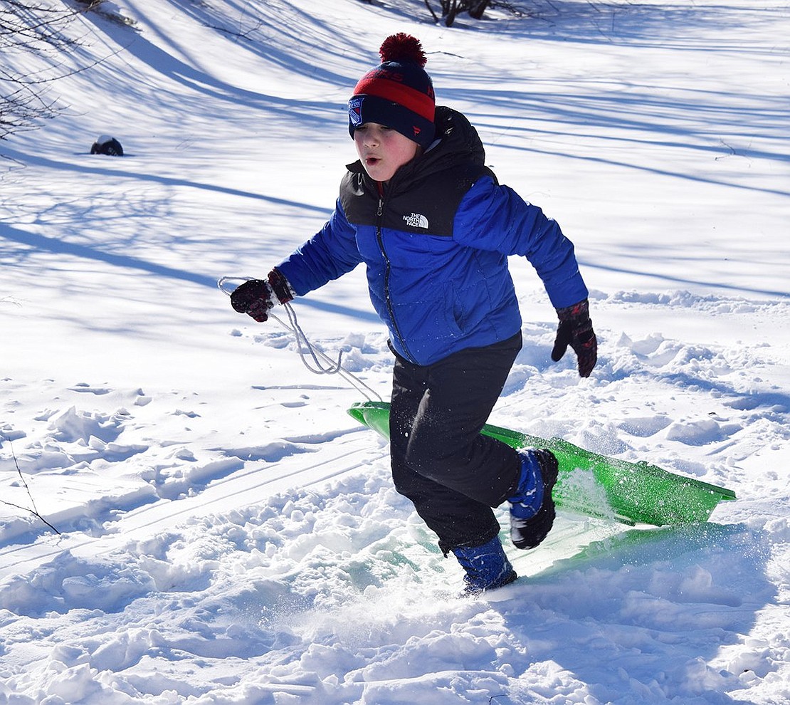 Jacob Mandell runs back up the hill with his sled, ready for another ride.