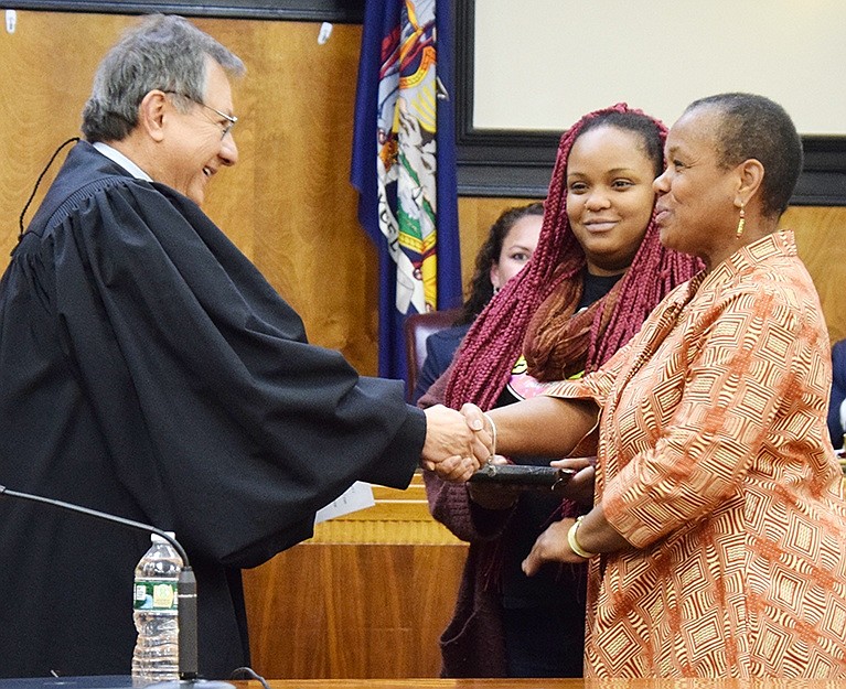 Trustee Joan Grangenois-Thomas, accompanied by her daughter Kiah, shakes hands with Rye Town Judge José Castaneda after he swears her in for a second term.