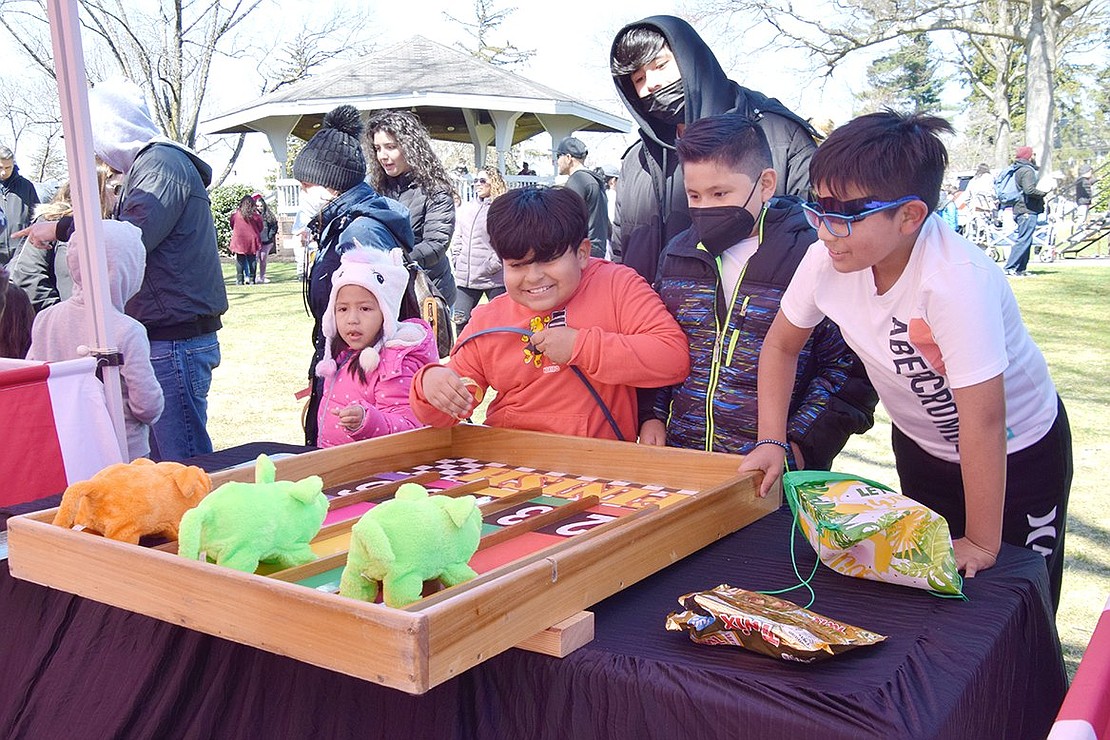 Hyped up by the competition, Corpus Christi-Holy Rosary School third-graders Nicholas Alfaro (left), Aaron Estraba and Jesus Ayala egg on their mechanical stuffed animals of choice, hoping to win at the piggy race carnival booth at Easter in the Park.