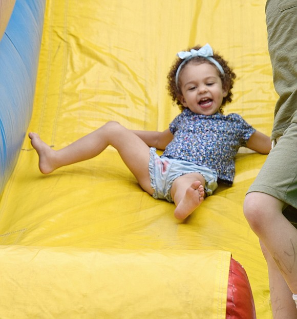 A White Plains resident visiting her family’s hometown of Port Chester, 2-year-old Aurora Romano is all giggles as she blasts down an inflatable slide at Lyon Park.