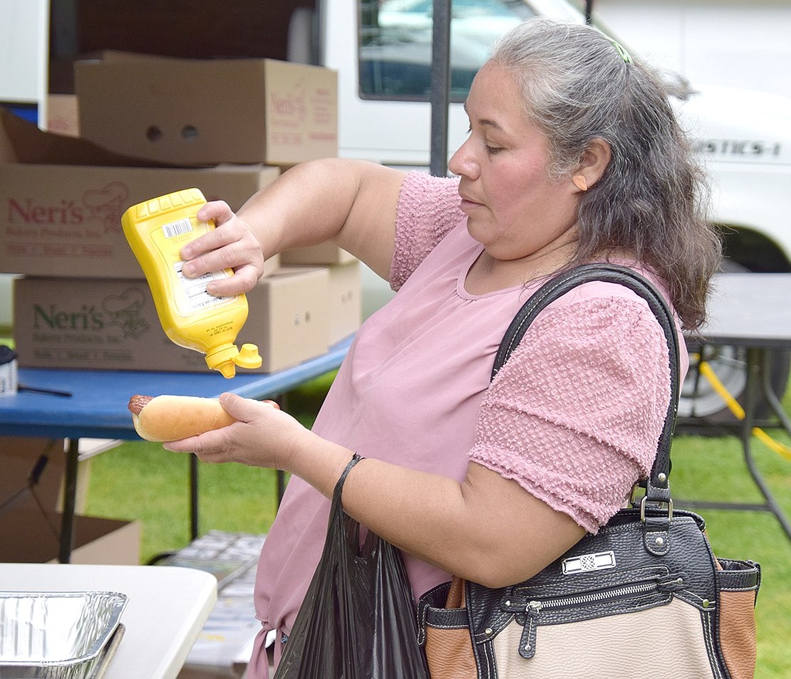 William Street resident Sonya Hernandez fixes up one of the hundreds of free hot dogs the Village of Port Chester provided guests.