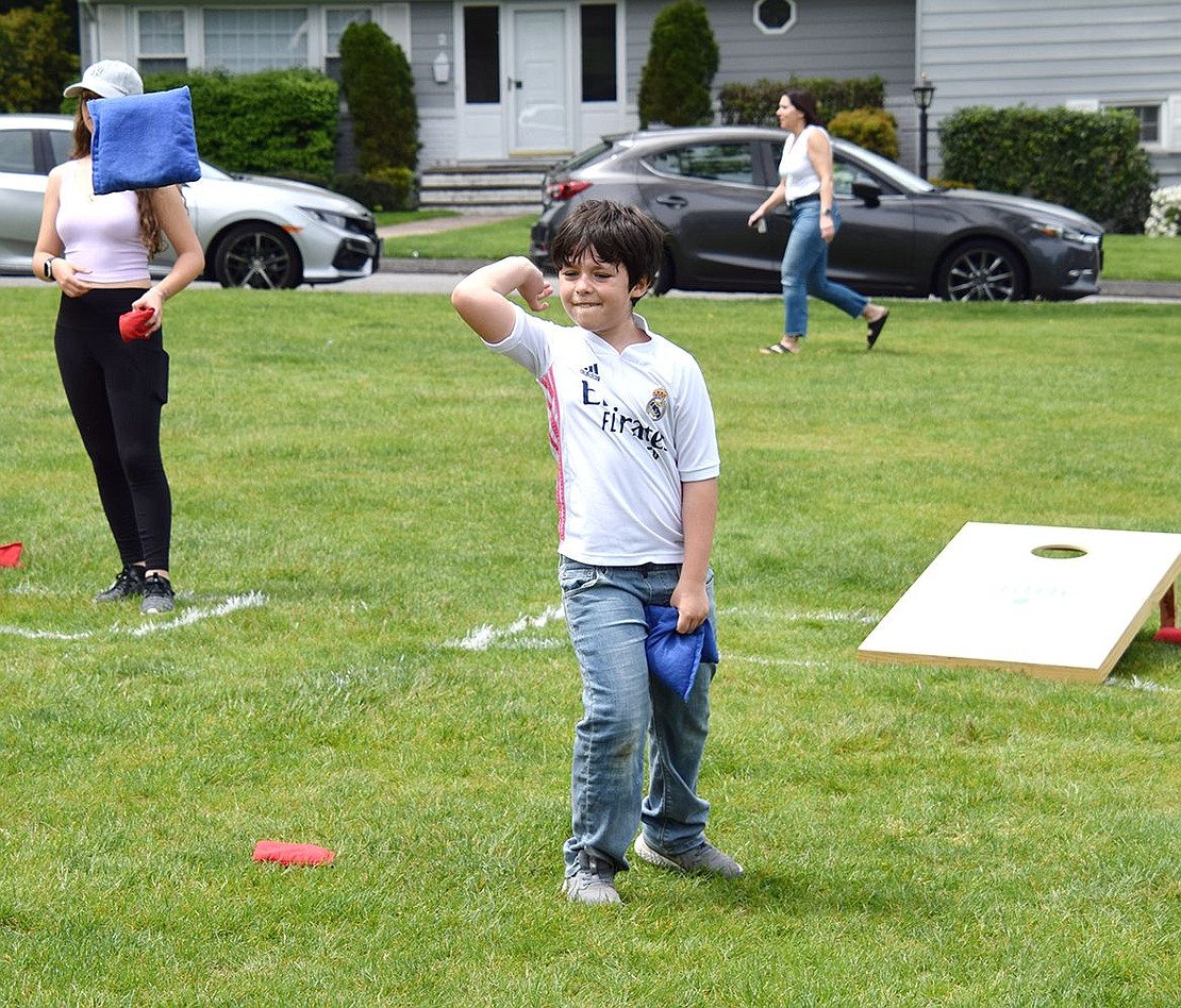 Trying his very best, Rye Brook 7-year-old Victor Luzuriaga throws a blue bean bag with might while building up skills for the game with his father.