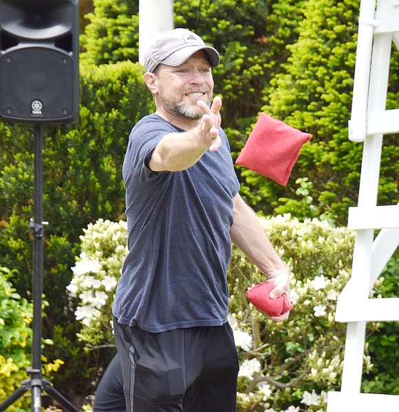 Knollwood Drive resident Luke Vnenchak hopes for the best as he tosses a red bean bag toward the board across the lawn.