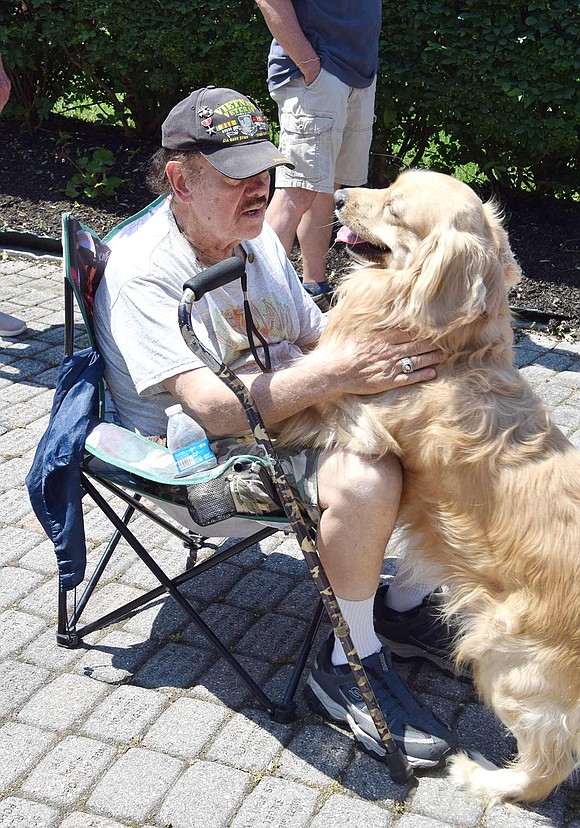 Richard Kochanowicz of Quintard Drive, a Vietnam veteran attending the ceremony at Memorial Park, gets some love from his companion Johnny, a mini-golden retriever service pet.