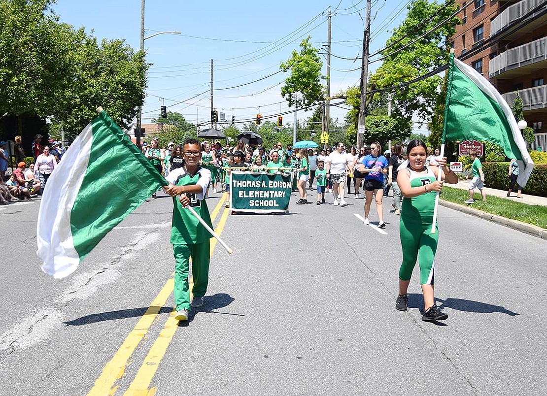 Dressed to impress in a fashion filled with school spirit, Edison Elementary School fourth-grader Steve Williams (left) and fifth-grader Daniela Navarro spin flags around while elegantly leading their classmates down Westchester Avenue.