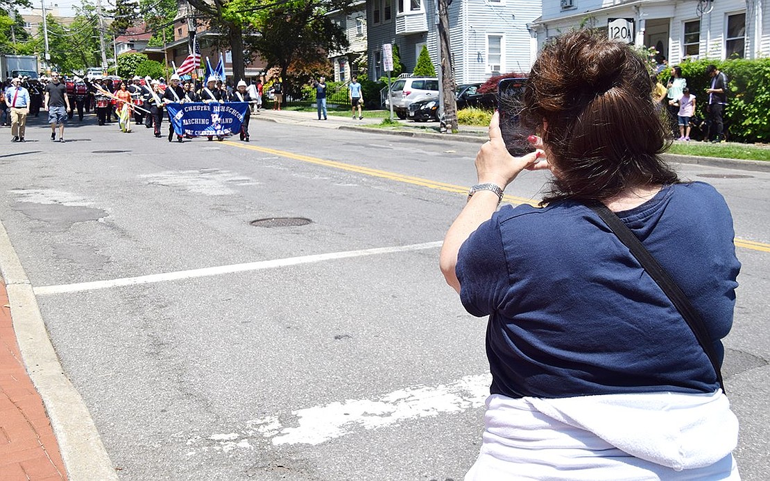 In an emotional state on the sidelines, longtime dedicated band parent Debra Scocchera takes out her phone to record her son Mark’s last parade as a senior with the Pride of Port Chester marching band.