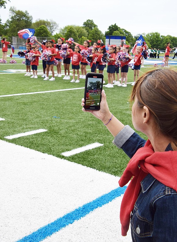 Parent Diana Camacho, who has two children in the group, films the Park Avenue School spirit squad performing on the field.