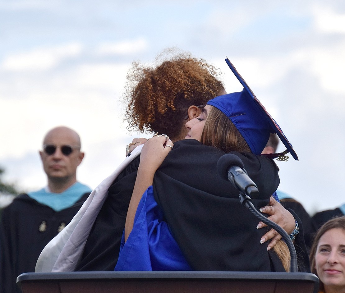 After Class of 2022 Co-Advisor Cher Treacy introduces Sydney Brookman to lead the crowd in saluting the American flag during the Blind Brook High School graduation ceremony on Thursday, June 23, she stops to give her a warm embrace. Treacy is the high school’s cheerleading coach, and Brookman was her captain.