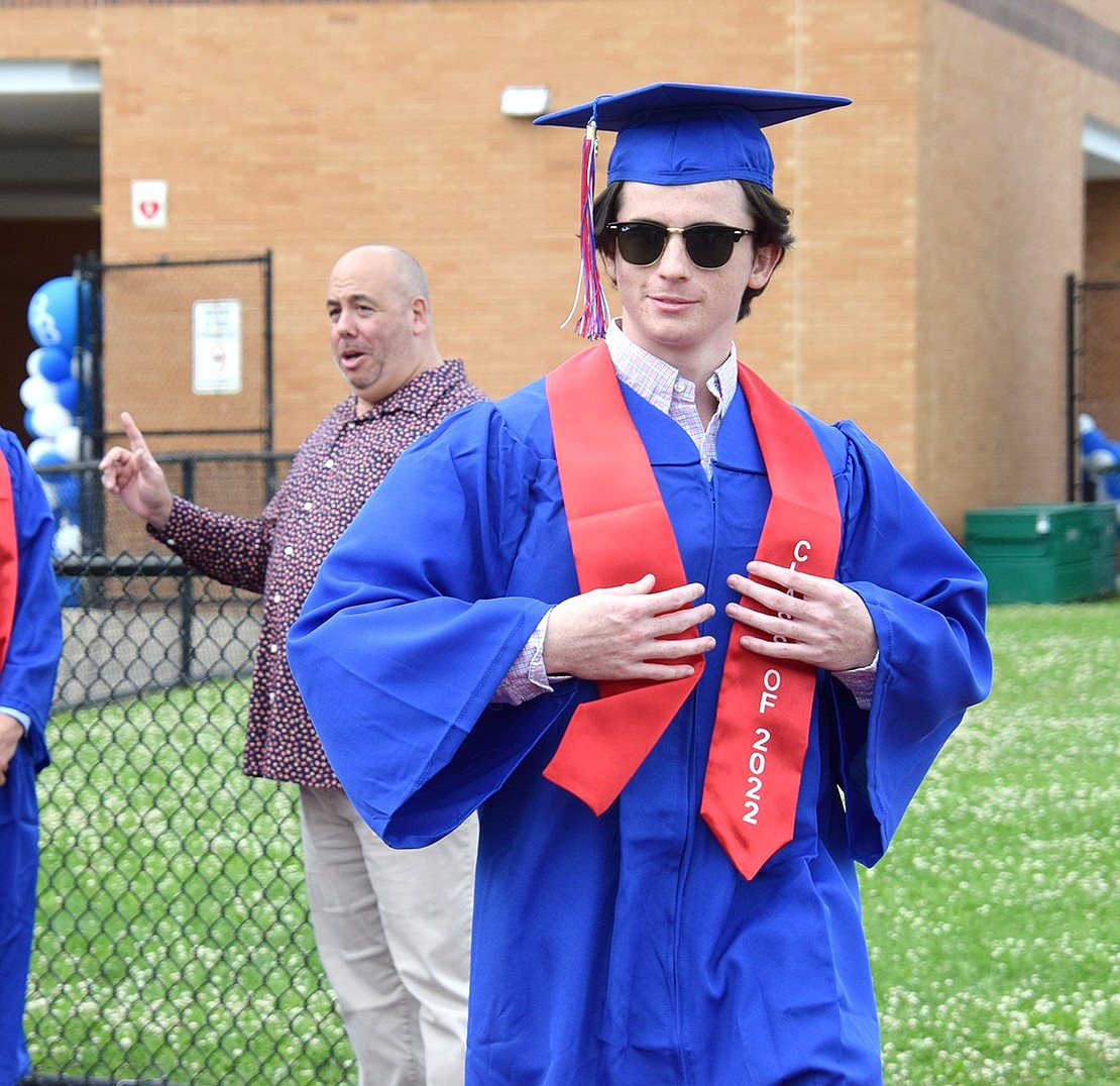 With swagger, Euan Scott straightens out his sash as he proceeds onto the Blind Brook High School football field for the commencement ceremony.