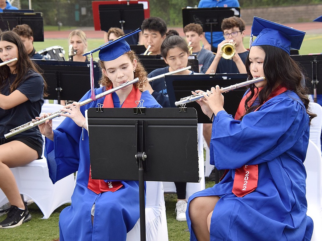 With matching caps and gowns, Rebecca Starr (left) and Kelly Ma stand out amongst their bandmates when they temporarily leave their seats to pick up their flutes and play the national anthem.