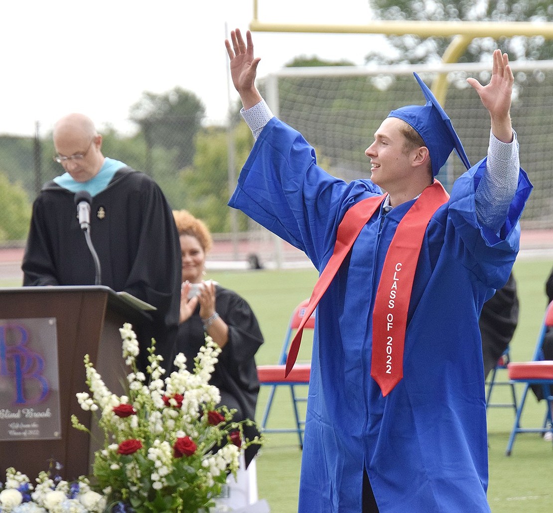 Once his name is called to receive his diploma, Connor Salvatore theatrically welcomes the cheers as he walks across the football field.