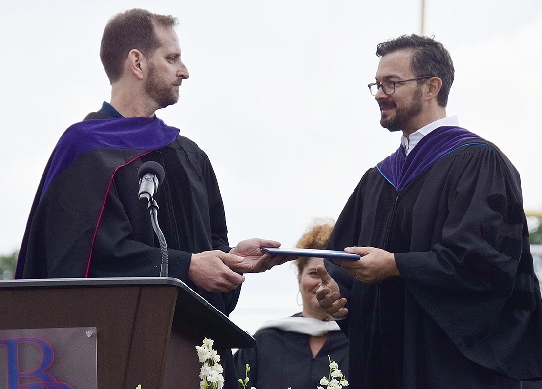 The first diploma of the night was technically given out by Board of Education President Scott Jaffee (left) to outgoing Trustee Ryan Goldstein—an honorary degree tributing his nine years of service to the district.