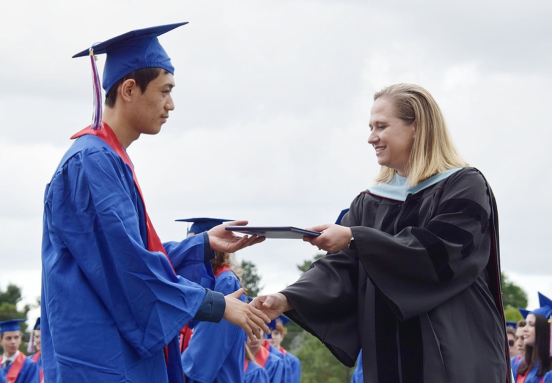 Moments after his name is called, Class of 2022 graduate Allen Bao graciously accepts a diploma and a handshake from Blind Brook High School Principal Dr. Jennifer Chirles.