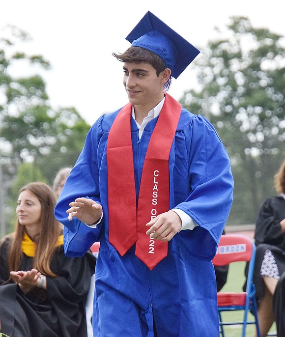 After his name is announced, Glenn Curreli gives a little wave to loved ones in the audience while he treks across the field to receive his diploma.