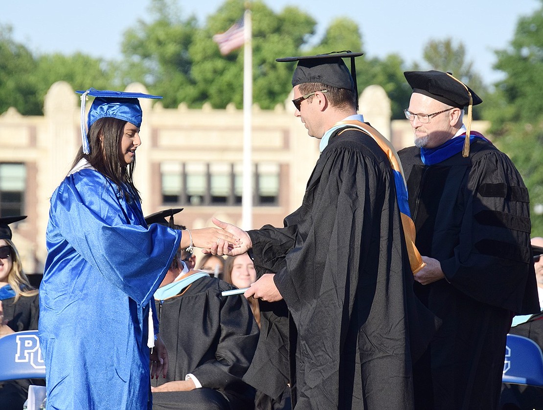 Once her name is announced, Class of 2022 Co-President Fatima Bautista shakes hands with Principal Luke Sotherden and accepts her degree.