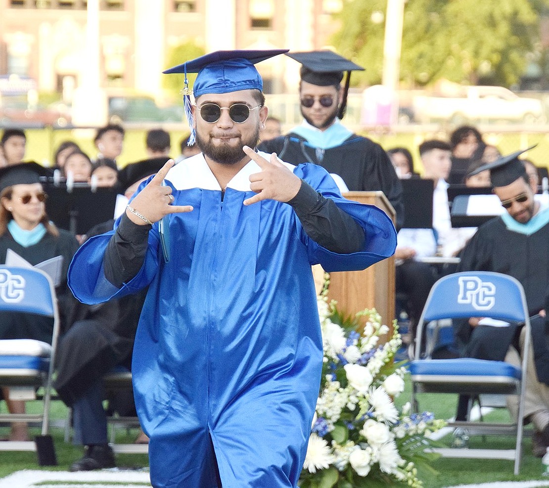 Diploma gets tucked and hand signs go up as Alejandro Leyva eagerly proceeds down the aisle after his name is called.
