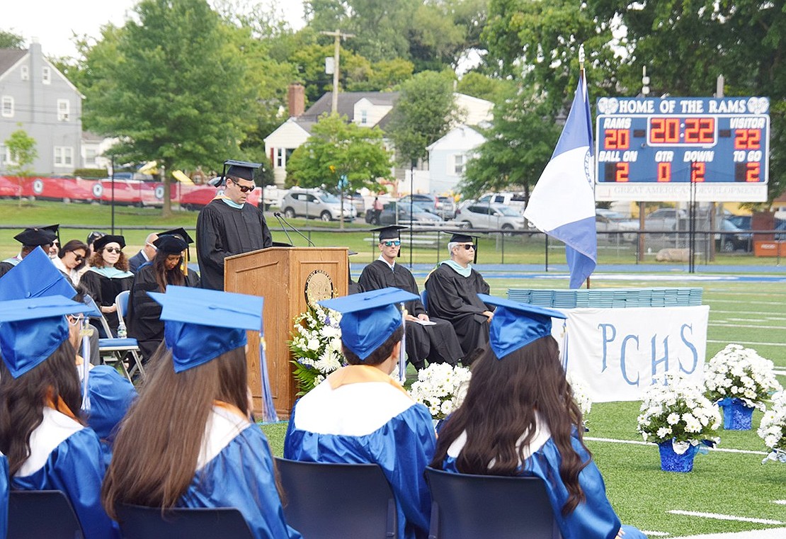 Shadowed by the football field scoreboard honoring the Class of 2022, Port Chester High School Principal Luke Sotherden addresses his graduating seniors before sending them off into the world.