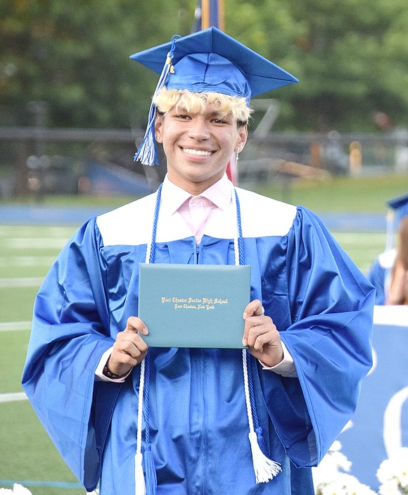 Beaming graduate coming through! Christian Torres smiles for the camera while clutching his freshly minted high school degree.