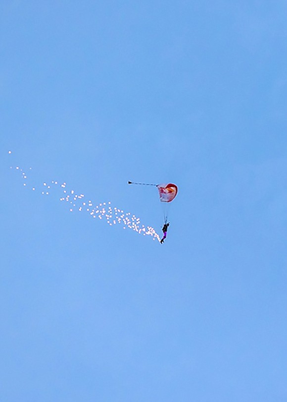 Port Chester native Jeff Provenzano appears tiny in the sky as his parachute opens over the Port Chester High School field.