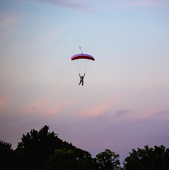 Skydiver Jeff Provenzano, who grew up near the high school, descends over the trees adjacent to Park Avenue School, eventually landing on the softball field.