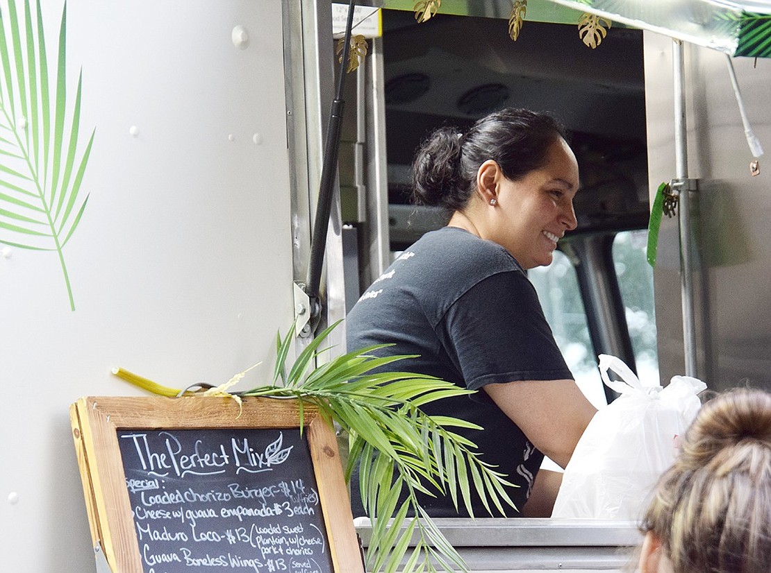 Brenda Delpezo, co-owner of The Perfect Mix food truck, smiles as she speaks with customers stopping for a quick bite to eat as they watch Goza perform. Delpezo and her husband own and operate Latusion and The Perfect Mix, the latter which serves Cuban-style sandwiches.