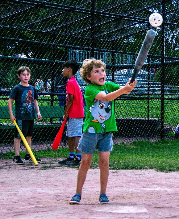 With all the might a 4-year-old can muster, Charlie Karasik attempts to hit the whiffle ball during the children’s game. Older teammates encourage the Loch Lane resident from the sidelines.