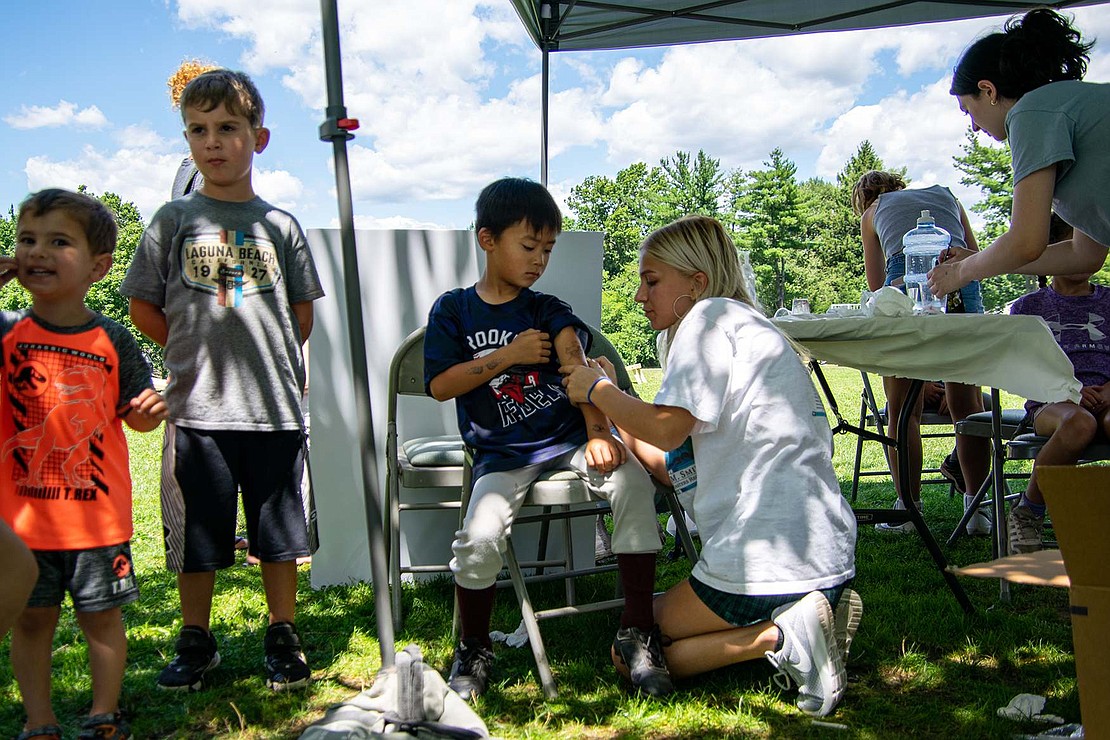 High Point Circle resident Noah Hashimoto, 6, patiently waits to get instantly cool as a volunteer administers a temporary arm tattoo. Body art booths were a staple of the Food Truck Event this year.