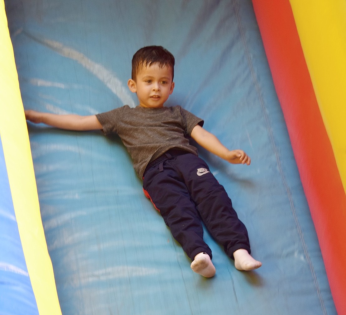 Though initially hesitant to make the leap, 3-year-old Port Chester resident Oscar Aguilar has no regrets zipping down the tall inflatable bouncy slide. In fact, once he was finished, he wanted to go again.