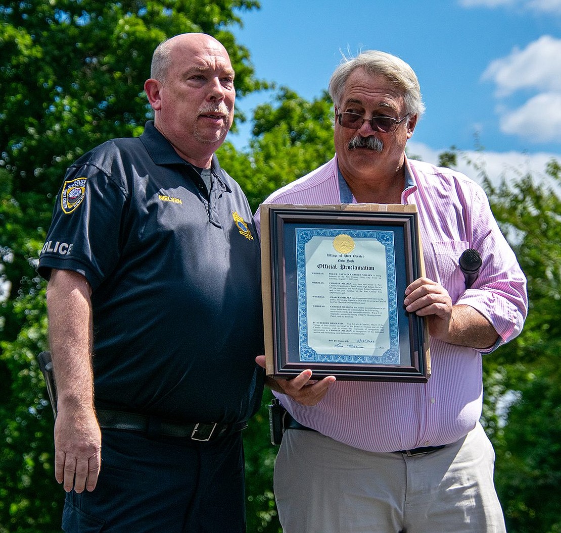 Port Chester Police Captain Charles Nielsen poses with Village Trustee Bart Didden, who presents him with a proclamation recognizing his service to the community.