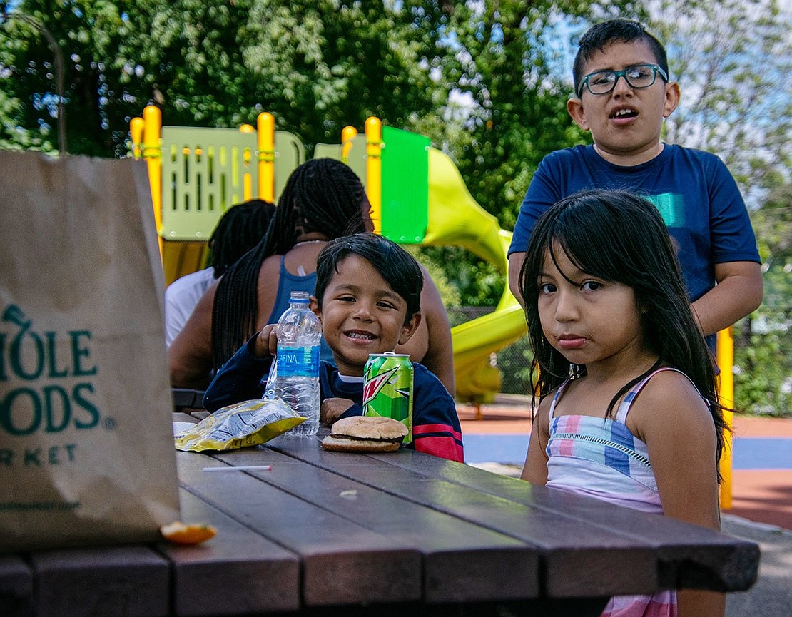 As a 4-year-old, Mia Ganan (front right) needs lots of fuel to stay energized, so she takes a break from playing to eat. The Soundview Street resident sits with her neighbors Marlon Durline, 5, and Niel Sanchez, 9.