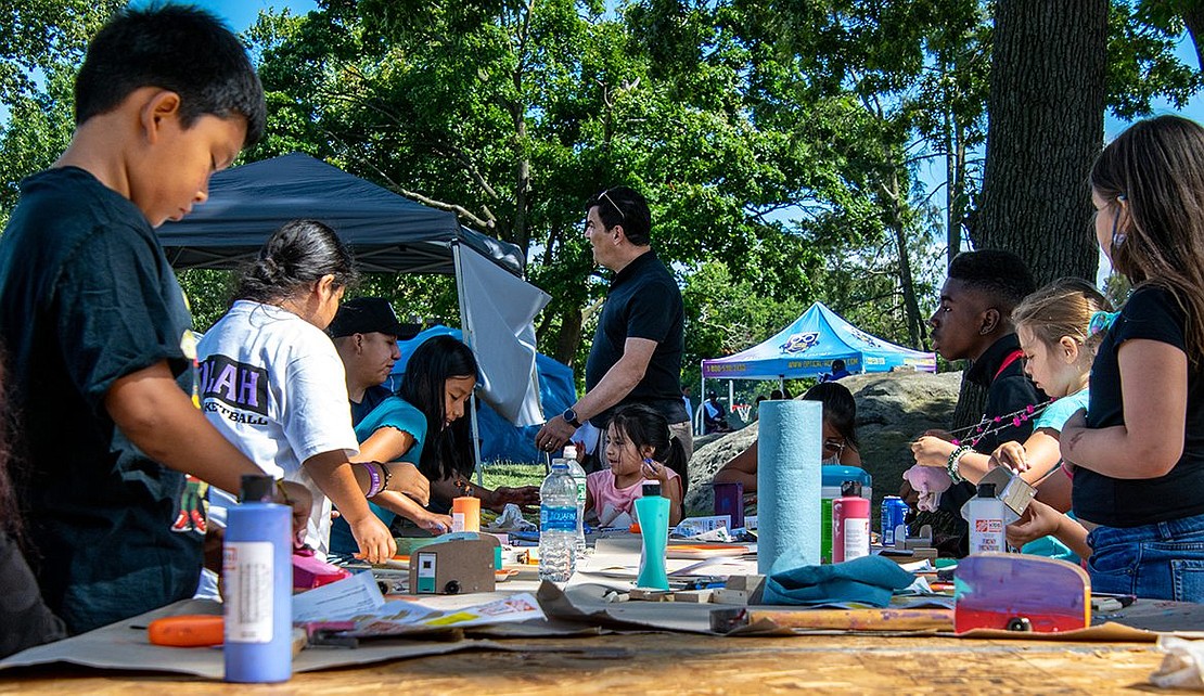 Children of all ages hammer and paint away at an arts and crafts table set up at the end of a line of vendor tents. Some sit with their parents, while others prefer working solo.