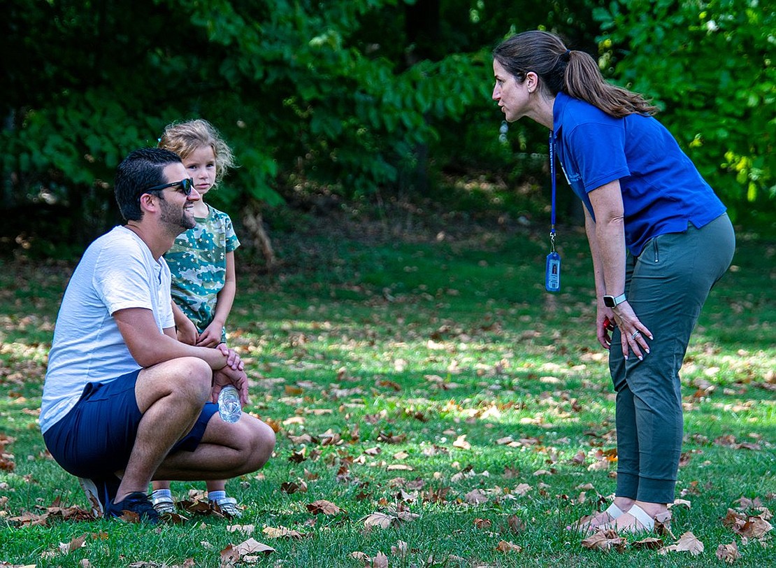 Mackenzie Gasparini, the solidarity coordinator of the Blind Brook Federation of Teachers and Blind Brook High School ninth-grade English teacher, speaks with shy first-grader Jordan Peikon and her dad, Zach. Jordan was scared to come to the event, but her conversation with Gasparini boosted her confidence.