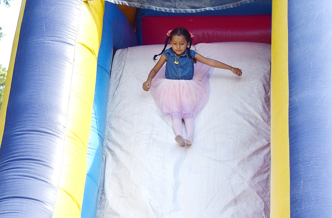 Dasure Diaz, a John F. Kennedy Elementary School rising first-grader, delicately fans out her tutu skirt and cautiously glides down the inflatable slide.