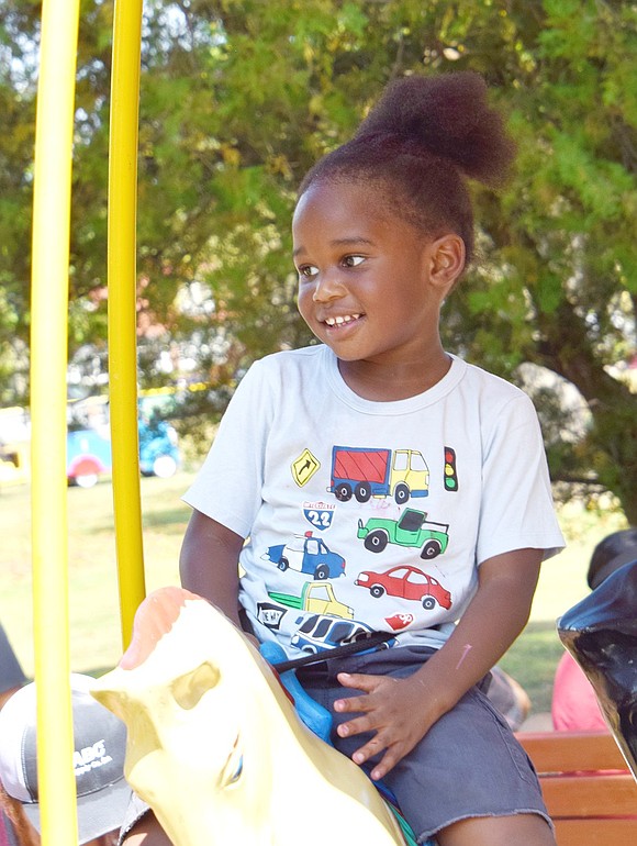 Thoroughly enjoying the circular motions of the merry-go-round ride, Elmont Avenue 3-year-old Brixton Calhoun gleefully beams at his mother watching from the sidelines.