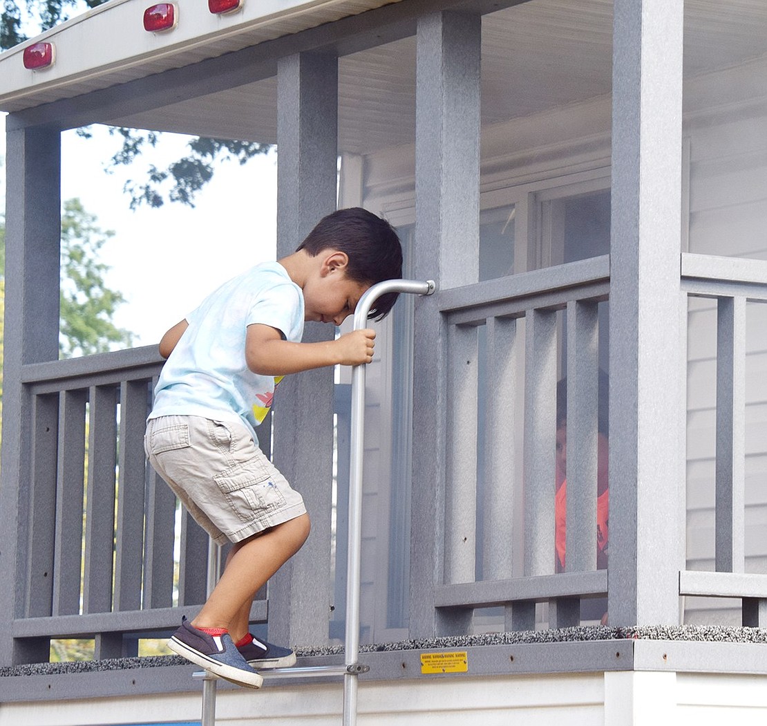 Escaping the smoke, Riverdale Avenue 4-year-old Santiago Bautista carefully climbs down ladder at the rear of the smoke trailer, showing off the skills he learned during a fire safety demonstration.