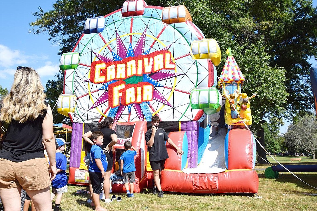 As the blazing hot sun shines down, children line up awaiting their turn to enter an elaborate bouncing house filled with light obstacles.