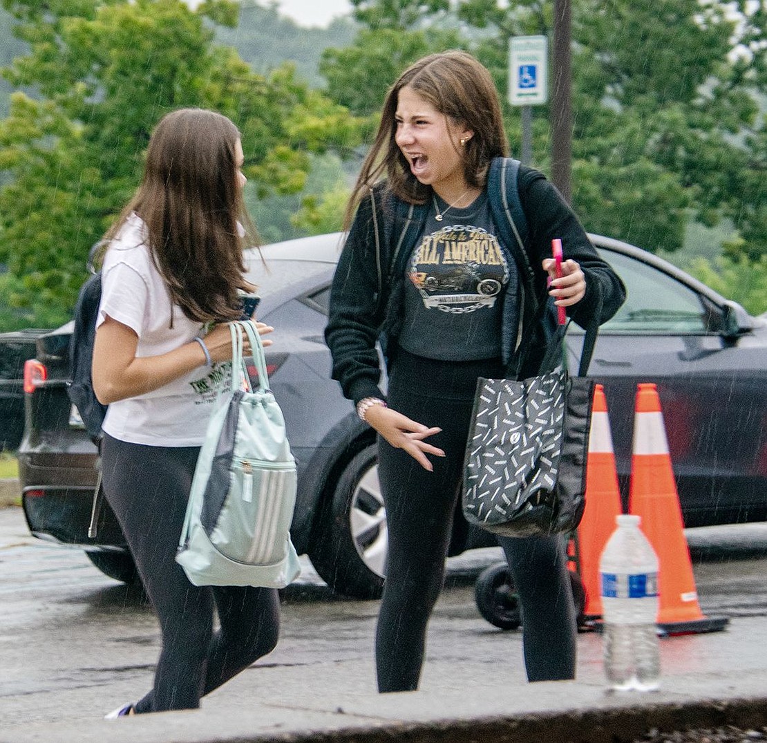 Rainwater soaks Julia Mensch (right) and Dylan Gold as they prepare to tackle their seventh-grade year. Mensch expresses her disgust for the weather before the two dash inside.