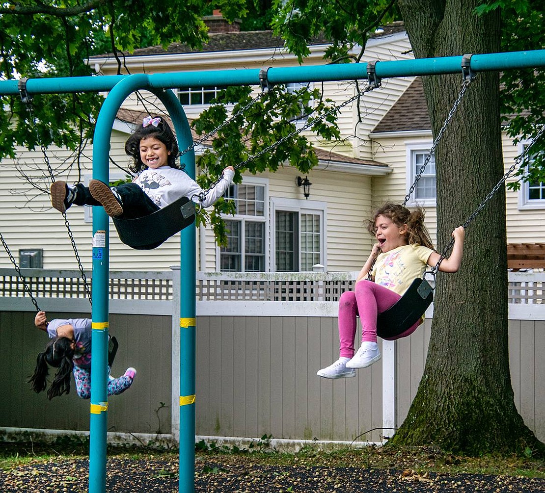 Selina Alvarado (left) giggles with glee as she swings higher and higher at a King Street Elementary School playground. The second-grader and her friend Alexis Tina, also a second-grader, perform tricks while they chat after a full day of class.